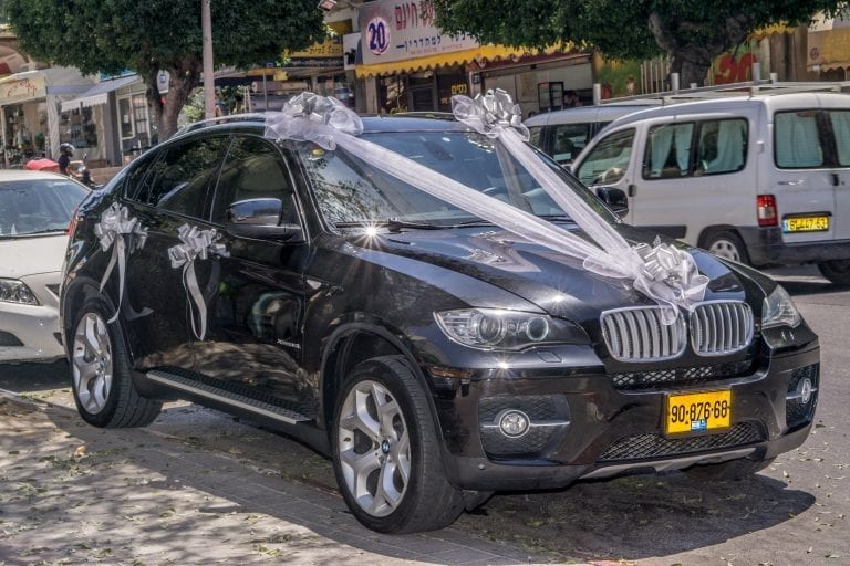 רכב ב‑MW שחור מקושט בסרטי טול לבנים ארוכים ופפיונים גדולים לחתונה